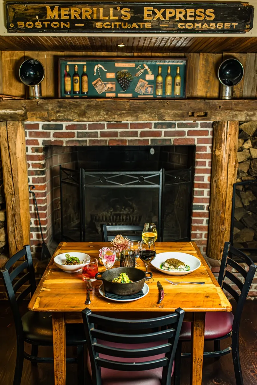 Fireside table set with wine and entrees inside The Red Lion Tavern